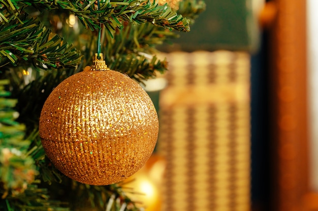 Beautiful golden bauble hanging from a Christmas tree