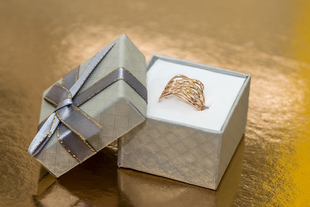 Beautiful golden jewellery in gift box on golden wall