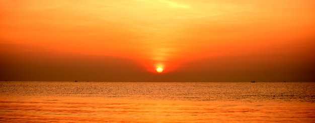 Фото Красивое золотисто-желтое небо и солнце вид на пляж, пляж и шезлонги растут. красивое золотисто-желтое небо и солнце