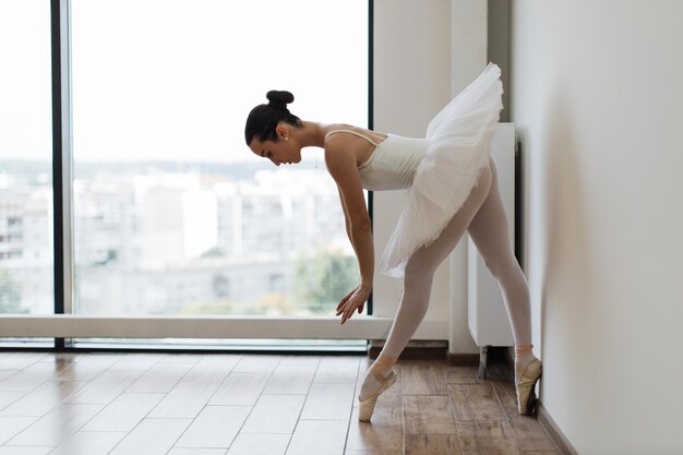 Фото Прекрасная грациозная балерина в белой практике балетных позиций