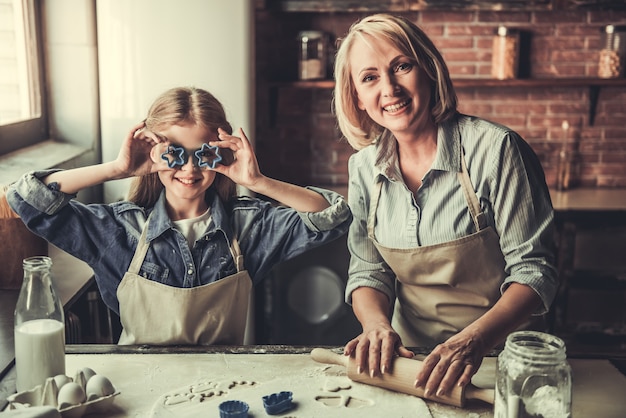 Beautiful grandma and granddaughter are cutting cookies.