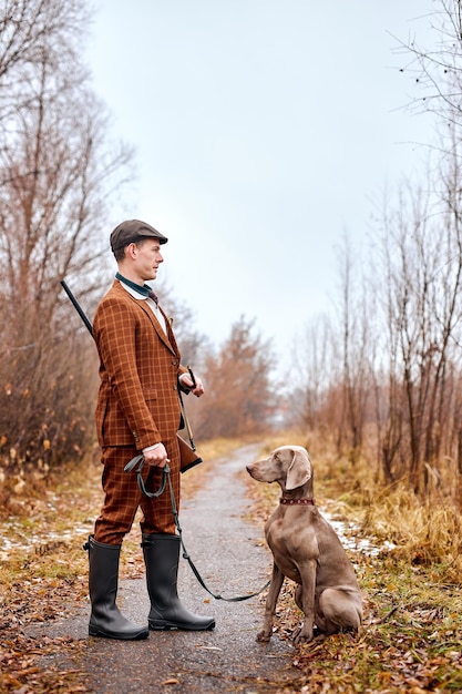 Beautiful gray hunting dog with owner during a hunting day autumn season hunter outdoors young cauca...