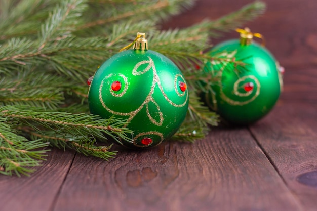 Beautiful green Christmas balls on a wooden background next to fir branches.Copy of the space.