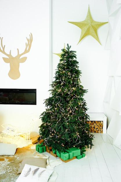 Foto un bell'albero di natale verde è decorato con una ghirlanda in una stanza bianca con una stella sul muro