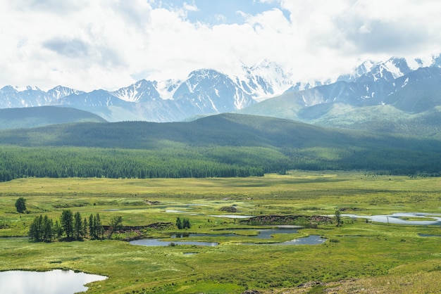 Beautiful green scenery with lake system on tableland among forest hills and snowy mountains. Scenic landscape with lakes group on plateau. Blue lakes system in wide valley. System of mountain lakes.