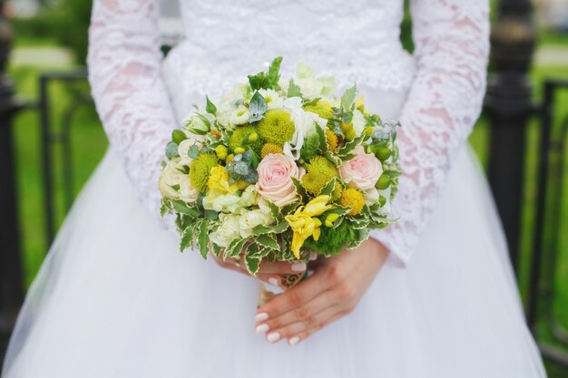 Beautiful green wedding bouquet in bride's hands, closeup