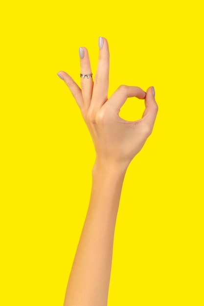 Foto bella mano della donna curata con il gesto giusto su colore giallo