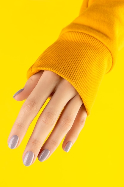 Beautiful groomed woman hand with trendy nail design on yellow