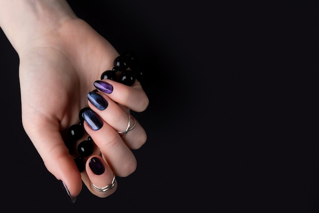 손톱에 어두운 반짝이 광택 디자인으로 아름 다운 손질 된 여자의 손