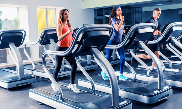 Beautiful group of fit friends exercising on a treadmill at the bright modern gym