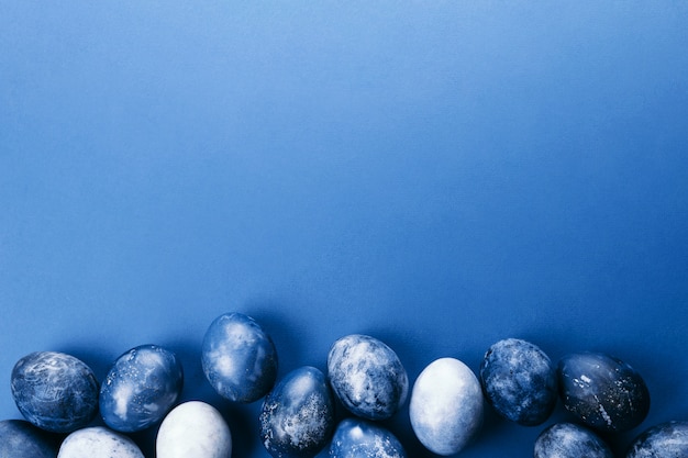 Beautiful group ombre blue Easter eggs with quail eggs and feathers on a blue background