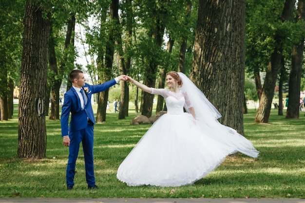 Beautiful guy and girl, bride in a white wedding dress, groom in a classic blue suit against a nature background. Wedding, family creation.