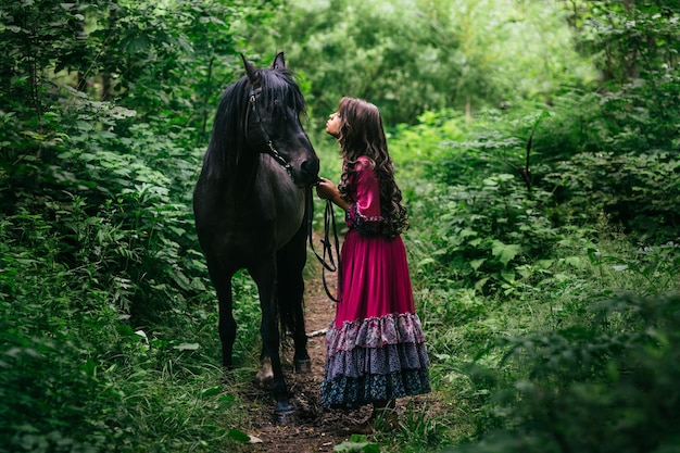 Beautiful gypsy in violet dress with a black horse