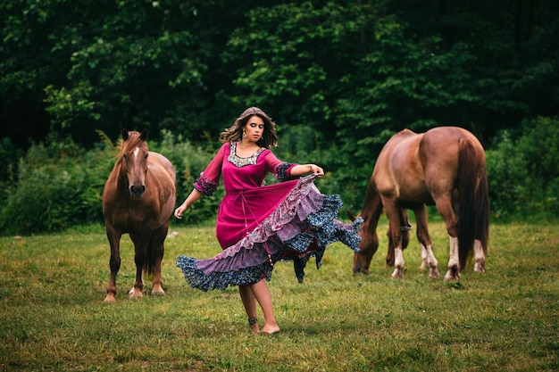 Beautiful gypsy in violet dress with horses