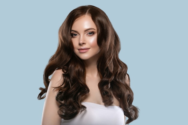 Beautiful hair skin woman portrait natural make up long curly hair. Color background blue