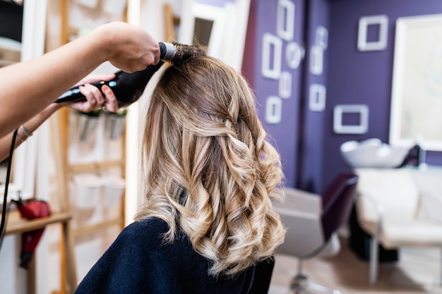 Bella acconciatura di giovane donna adulta dopo aver tinto i capelli e messo in evidenza nel parrucchiere.