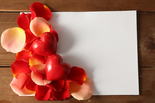 색 나무 배경에 장미 꽃잎이 있는 아름다운 손으로 만든 엽서