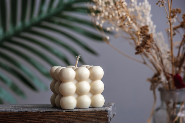 Beautiful handmade candle of interesting shape on a wooden stand