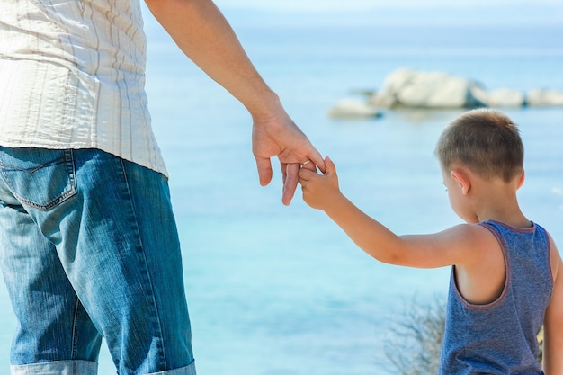 Красивые руки родителей и ребенка на берегу моря