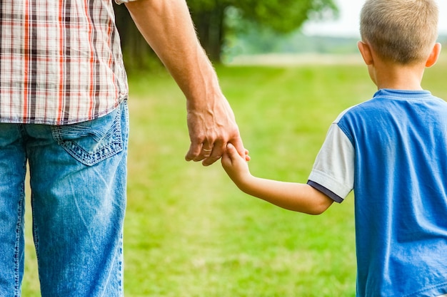 Beautiful hands of parent and child outdoors in the park