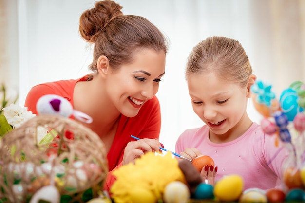 Beautiful happiness mother and daughter painting Easter egg at home.