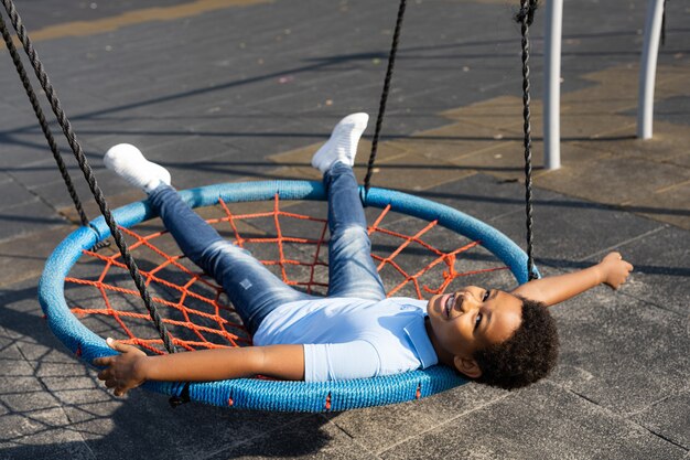 Beautiful happy african american family bonding at the park - Black family having fun outdoors, cute boy playing at the swing