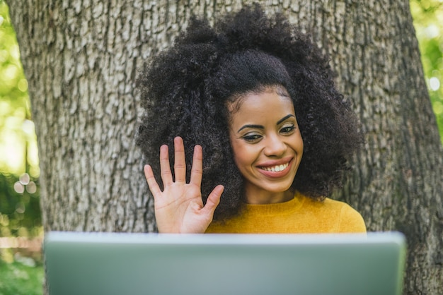 Beautiful and happy afro woman talking on video call with a\
laptop in a garden. selective focus.