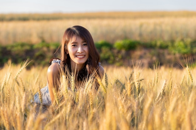 Beautiful and happy asian woman enjoying life in barley field at sunset.