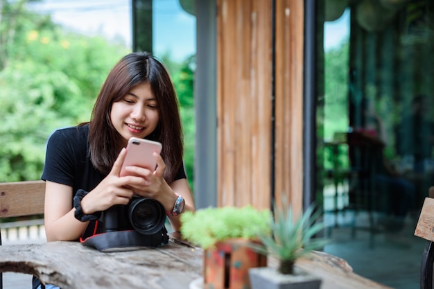 Beautiful and Happy Asian Woman holding Camera in the Garden.