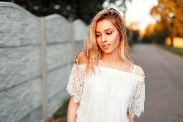 Beautiful happy blond woman with a smile in a vintage lace white T-shirt on summer day outdoors