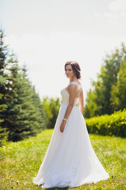 Beautiful happy bride dancing and spinning in the park in her wedding day.