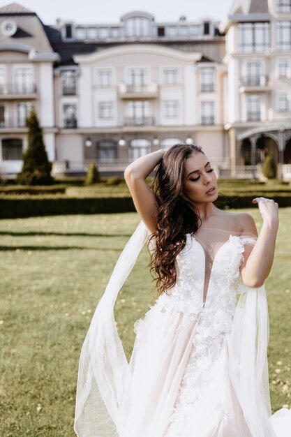 Beautiful happy brunette bride in white dress posing in sunset