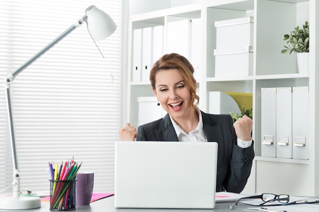 Beautiful happy business woman celebrating with arms up