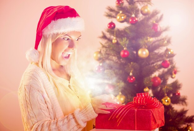 Красивая счастливая рождественская девушка со светящимся рождественским подарком.