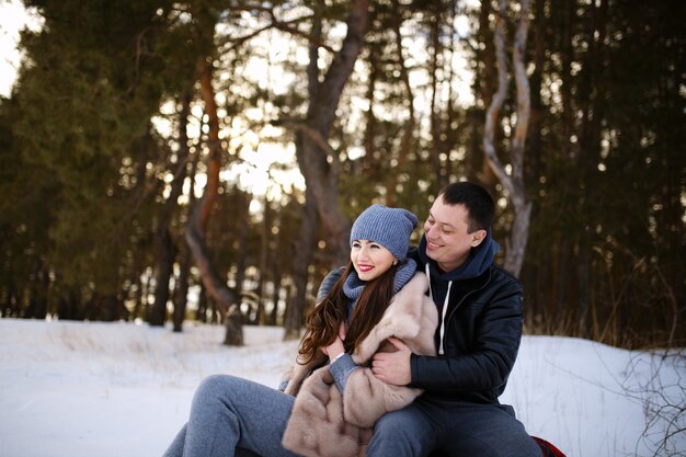 Beautiful and happy couple in love sitting on a blanket in winter in a snowy forest