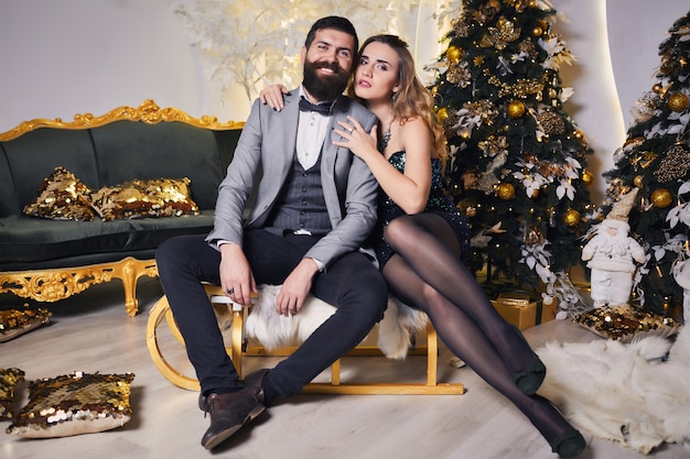 Beautiful happy couple with Christmas winter sleigh in the decorative interior of the New Year