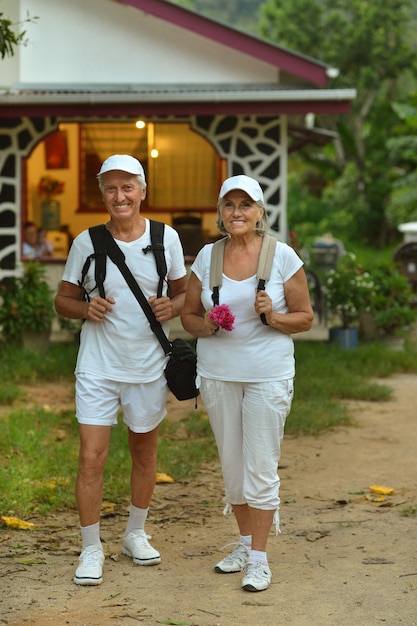 Photo beautiful happy elderly couple rest at tropical resort with backpacks