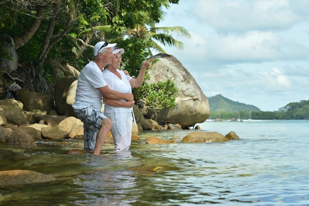 Bella coppia di anziani felici riposa al resort tropicale, donna che indica con la mano