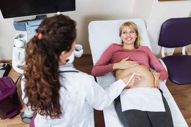 Bella e felice gestante che fa l'ecografia nella clinica prenatale.