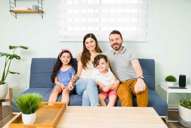 Beautiful happy family of four smiling and making eye contact while sitting at home during a relaxing leisure day