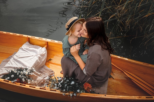 Beautiful happy family mother and daughter in a wooden boat  on the lake together