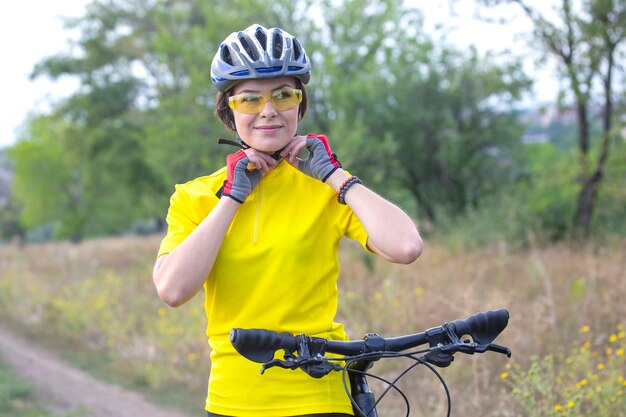 Красивая и счастливая девушка-велосипедист с велосипедом на природе. Здоровый образ жизни и спорт. Досуг и хобби