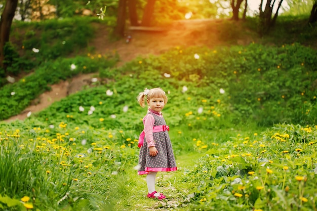 日当たりの良い春の夜に黄色の花のフィールドで遊んで美しい幸せな女の子