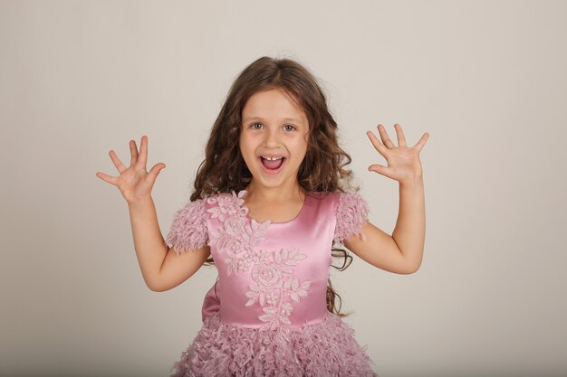 Foto bella ragazza felice con i capelli ricci in un vestito rosa