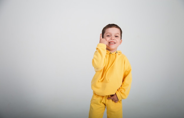 Beautiful happy little boy in a yellow suit on a white bac