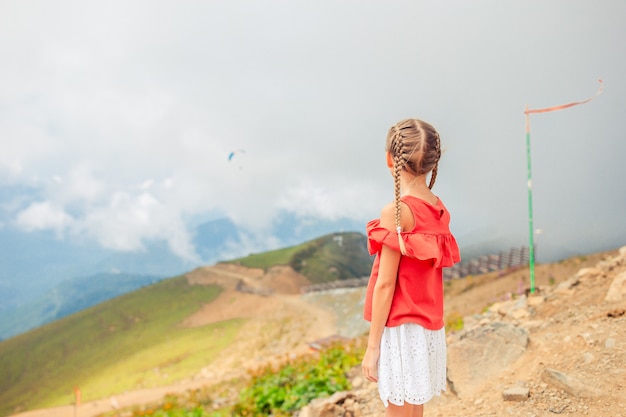 Beautiful happy little girl in mountains in the background of fog