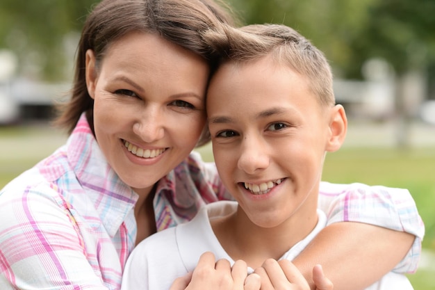 Beautiful happy mother with son posing in summer park