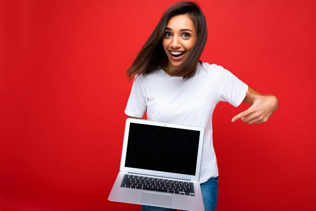 Bella giovane donna felice e contenta con un taglio di capelli corto bruno scuro che tiene in mano un computer portatile con