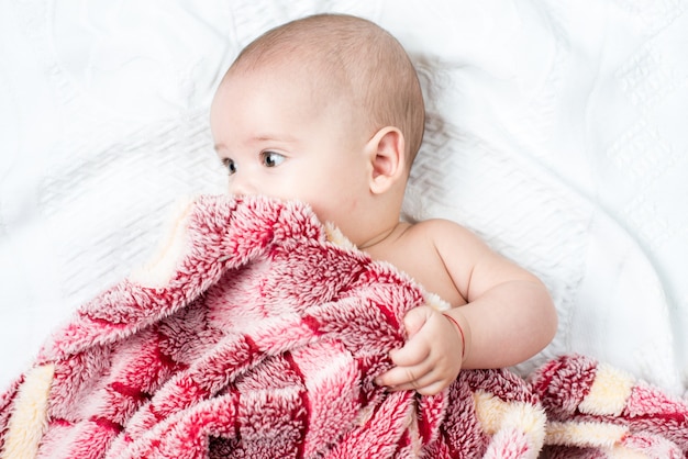 Beautiful happy small baby girl lying in bed