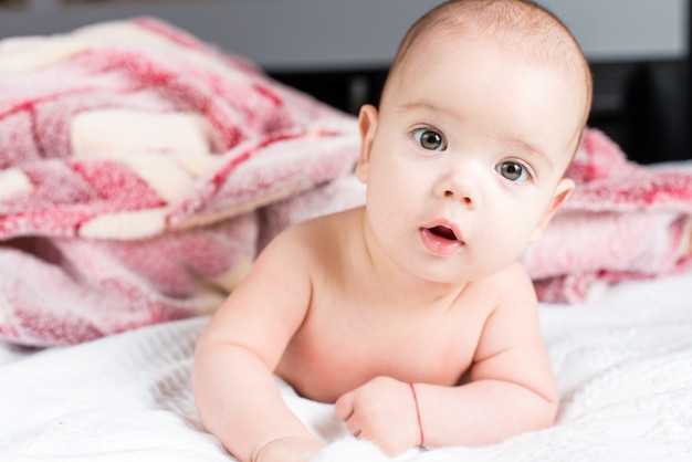 Beautiful happy small baby girl lying in bed